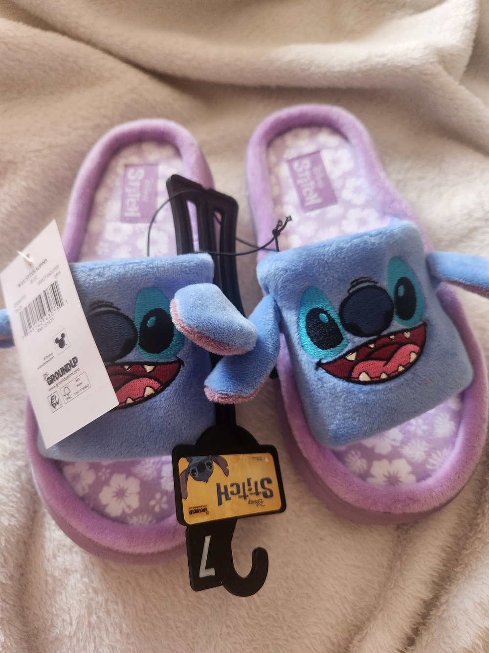 Plush slip-on slippers with Stitch character faces. Blue upper with lavender tri